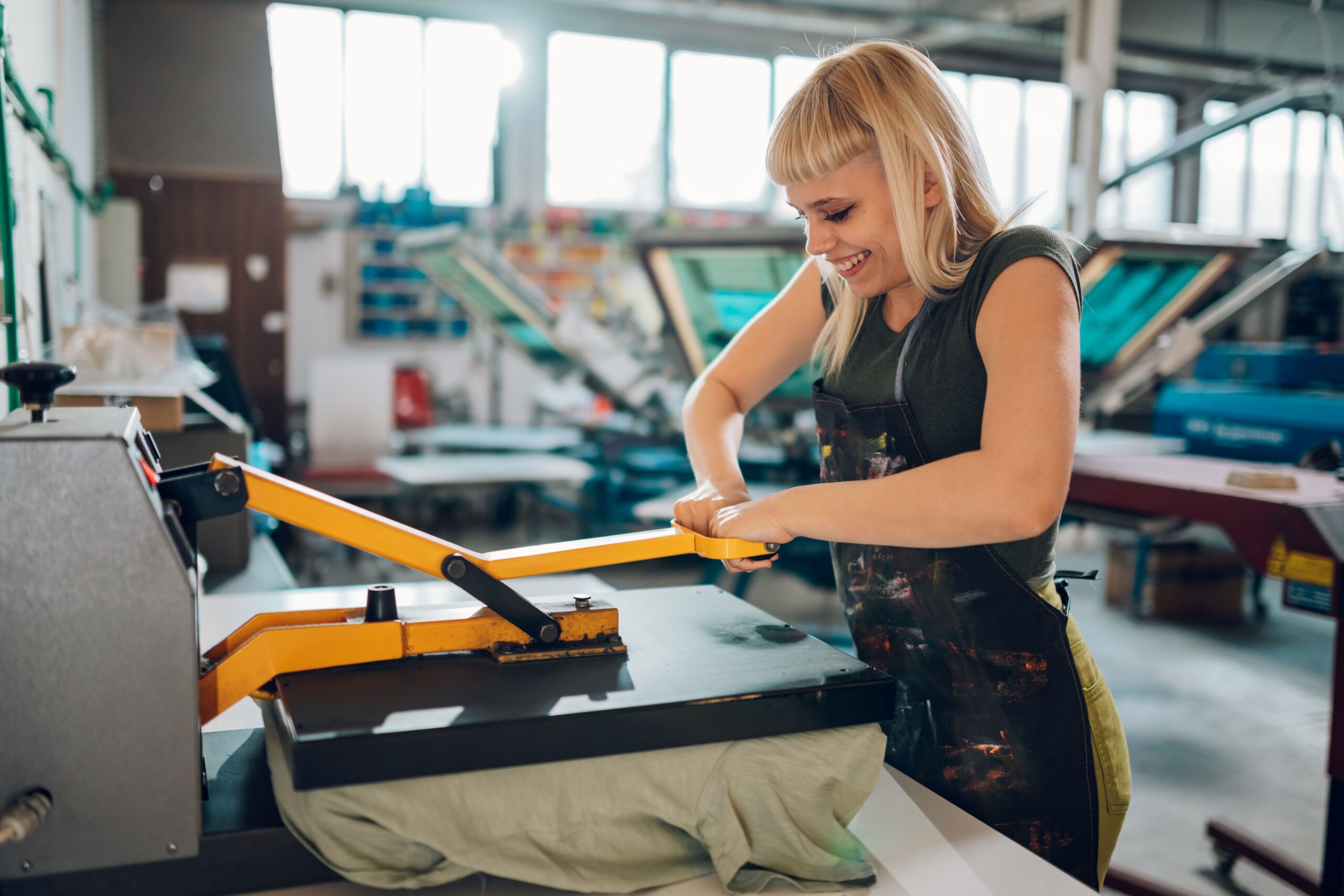 Example of a transfer being applied to a shirt using a heat press machine in a screen printing shop.